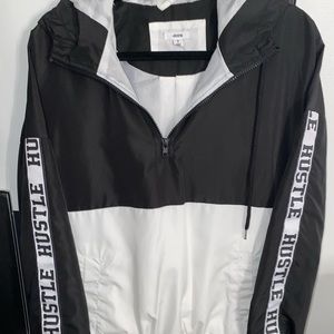 White and black windbreaker with hustle written down the sleeves